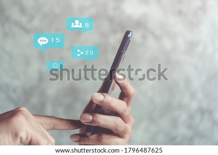 Hand typing keyboard with smartphone with social media and marketing virtual icons screen concept.