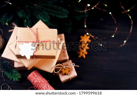 Christmas composition with many craft gift boxes, fir branhes and gingerbread on dark wooden table. Holiday concept background, top view, copy spase