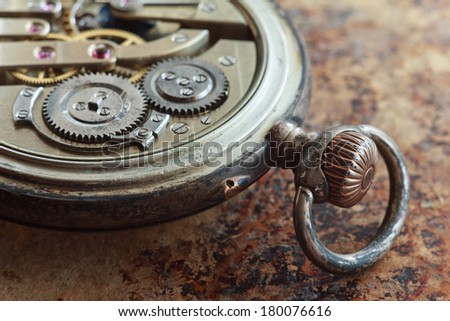 Close up view of the gears and mainspring in the mechanism of a silver pocket watch on old paper 