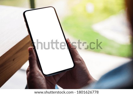 Mockup image of a woman holding mobile phone with blank white desktop screen 
