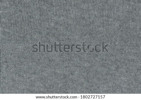 Grey knitted fabric texture. Light grey knitted knitwear. Natural fabric.