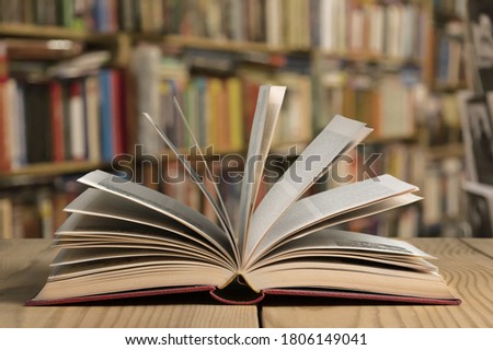 Open book on the table in the library shelf background