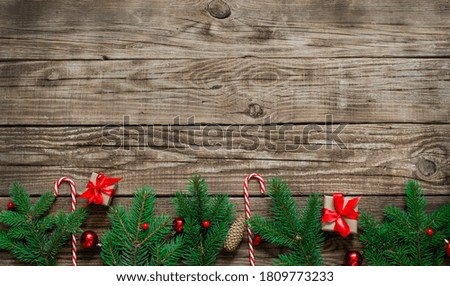 Bright Christmas arrangement of fir tree branches, sweet red canes, red Christmas balls on wooden background. Winter holidays, New Year.Flat lay, top view, copy space. Banner