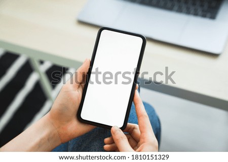 Woman hand holding smartphone and touching blank screen. Mockup of advertisement.