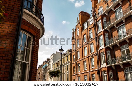 Looking up at red brick London townhouses against blue sky