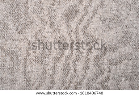 Knitted beige fabric. Fabric texture. Needlework.