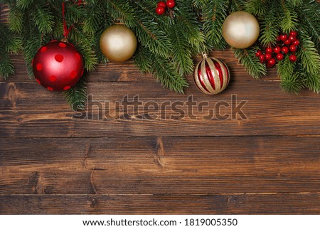 New Year and Christmas mock-up with fir tree branches and red and golden decorations on the wooden background with copy space in the bottom
