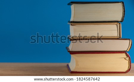 stack of four books lies on a blue background on an oak table. Background for design. Web banner.