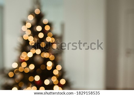Blurred light on Christmas tree. Bright glow gold bokeh. Reflections of Christmas lights.