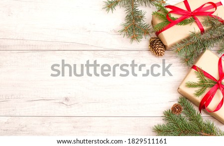 Merry Christmas frame and wallpaper. Happy New Year composition. Christmas gift, pine cones, fir branches on wooden white background. Top view and copy space