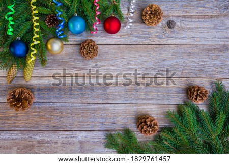 Wooden Christmas background with fir branches, Christmas balls, pine cones and serpentine
