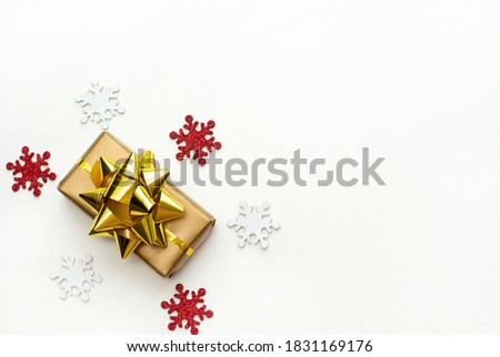 Christmas gift box with gold ribbon on a white background with shining snowflakes. Flat lay. Copyspace.