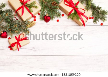 Merry Christmas frame and wallpaper. Happy New Year composition. Christmas gift, red berries, heart shape balls, pine cones, fir branches on wooden white background. Top view and copy space
