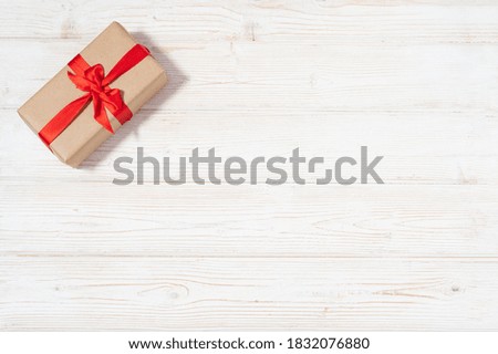 Present craft box with red decoration flat lay with copy space on the wooden white natural wooden table background. Holiday event gift