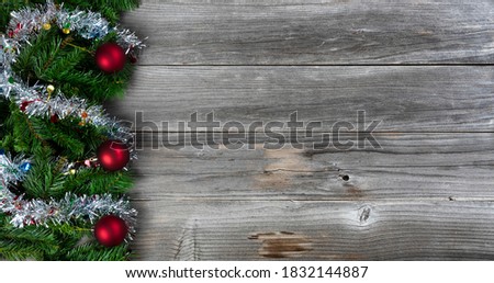 Merry Christmas and Happy New Year holiday concept with silver tinsel and red ball ornaments on rustic wood 