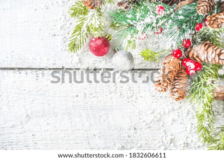 Christmas and New Year greeting card background. Xmas backdrop with fir tree branches, decoration and snowfall on wooden white board 
