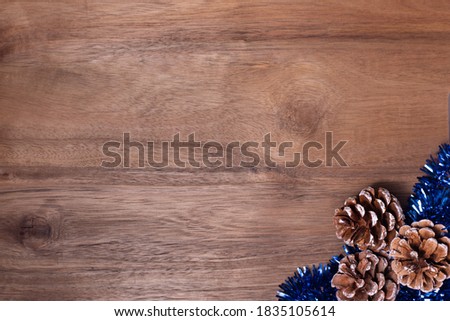Christmas frame pine cones and blue tinsel on wooden background
