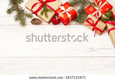 Christmas background and wallpaper. New Year composition. Christmas gift, red berries, heart shape ball, pine cones, fir branches on wooden white floor. Top view and copy space