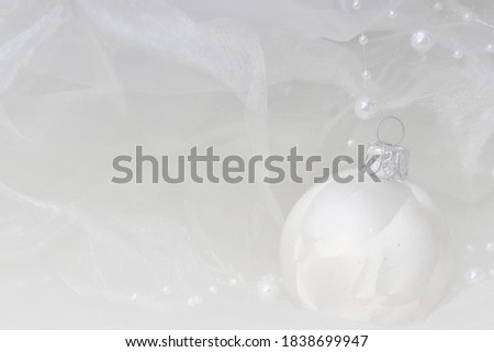 white christmas ball on white background with pearls and silk, focus on the right side