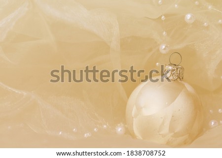 golden christmas ball on golden background with pearls and silk, focus on the right side