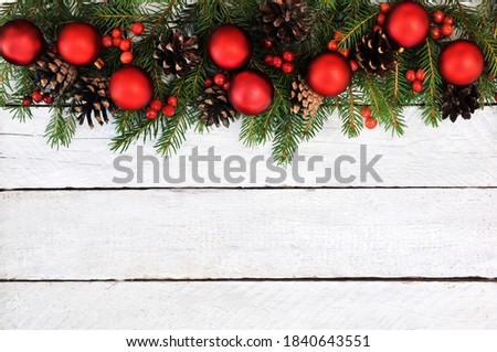 Red balls on fir branches, bells, pines, red berries background; festive Christmas and New Year celebration card, toned	