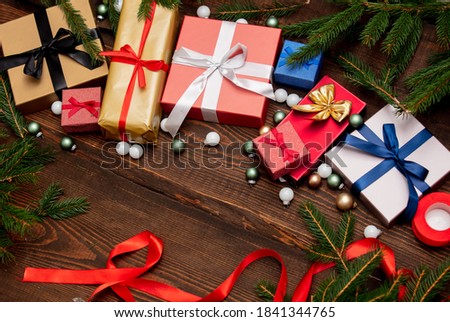 Christmas gifts and pine branches with baubles on wooden table 