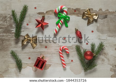 Red Christmas toys, spruce branches and Christmas sweets on a wooden background. Meeting of Christmas and new year.