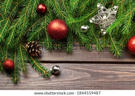 Winter holidays decorations with fir tree branches on dark wooden background. Christmas red balls, cones and silver star