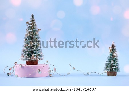 Christmas trees or New Year trees with Christmas decorations and pink bokeh lights on trendy blue background with copyspace for your text. Selective focus, place for text