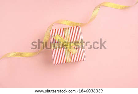 The box with a gift of dyes is packed with gold ribbon on a light background. A place for text. Flat lay