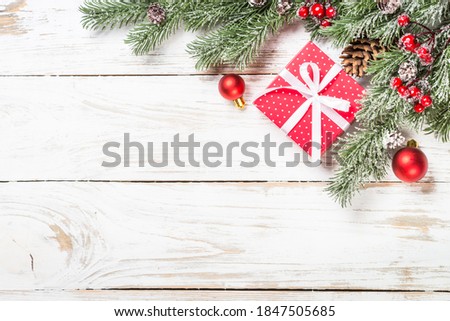 Christmas background with fir tree, present box and decorations at white table. Top view with copy space.
