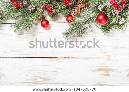 Winter fir tree with berries, pine cones and snow at white table. Top view with copy space.