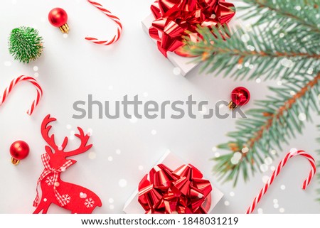 Gift boxes background. White gift box with red ribbon, New Year balls and sparkling lights in Christmas composition on white for greeting card. Winter festive composition with copy space.