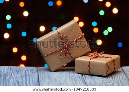 Christmas or New Year gift boxes on a wooden surface against a background of colorful lights
