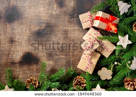 Christmas gift boxes made of craft paper under spruce branches on a brown wooden background. Copyspace