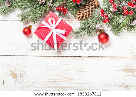 Christmas background with fir tree, present box and decorations at white table. Top view with copy space.