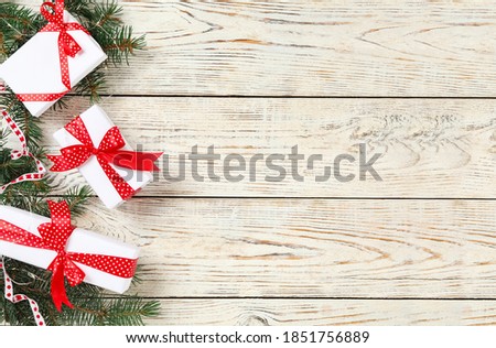 Christmas gift boxes with red bows and fir branches on white wooden background, flat lay. Space for text