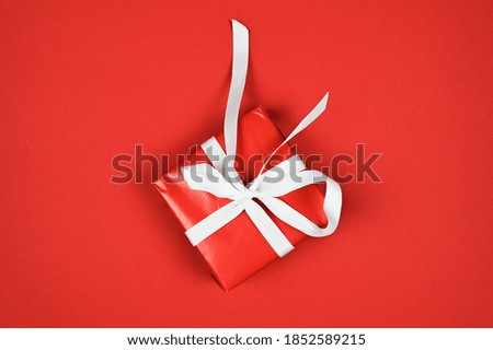 Red gift with white ribbon on red background