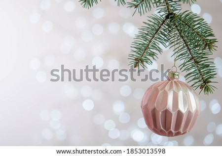 A pink ball hangs on a Christmas tree branch. Bokeh. Christmas decoration