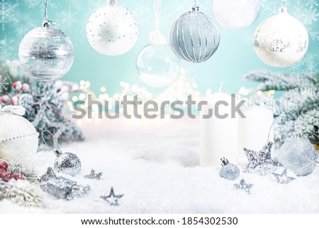 Christmas silver and white decorations on snow with fir tree branches and christmas lights on blue background