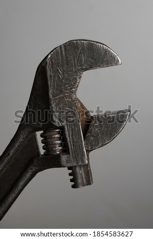 old tool, adjustable wrench on a gray background close-up.Old metal tools.