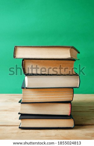 Stack of books on green background, many books piles, bookshelf