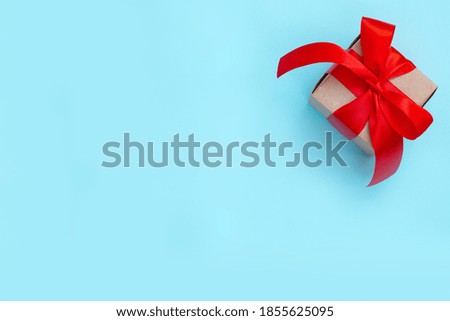 Gift box with a red bow on a pastel blue background. Minimal festive composition. Copy space for text.