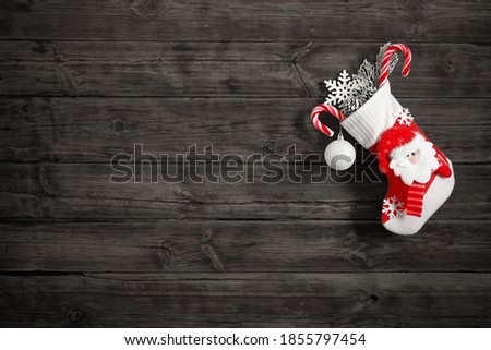 Christmas stocking with gifts hanging on dark old wooden background