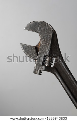 old tool, adjustable wrench on a gray background close-up.Old metal tools.