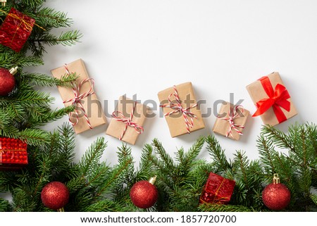 Gift boxes in craft paper.  Christmas gifts under spruce branches decorated with wooden ornaments on a white background. Copyspace	