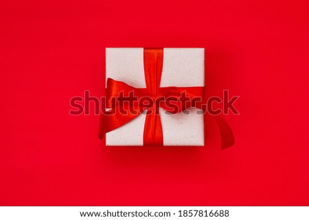 Gift box with a Christmas bow on a red background with copy space.Christmas composition. Flat lay, top view. Minimalistic style.