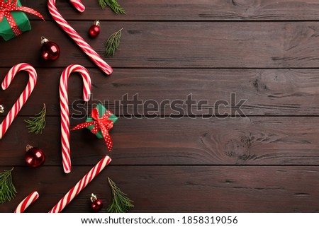 Flat lay composition with candy canes and Christmas decor on wooden table. Space for text
