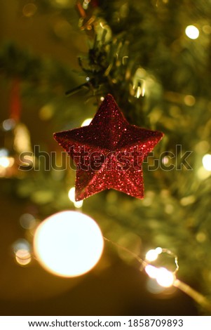 Christmas tree decoration with red glitter star and bokeh blurred background