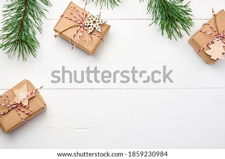Christmas gift boxes with pine tree branches on white wooden background